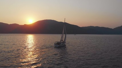 Fototapeta premium Yachting, a beautiful white yacht is sailing off the coast. Pink sunset