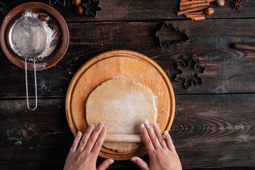 Christmas and New Year celebration traditions. Family home bakery, cooking traditional festive sweets. Woman rolling gingerbread dough with rolling pin on pastry board
