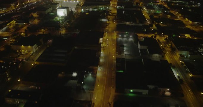 Aerial shot, night, fly over large la side streets and pan up to view downtown la at distance, drone