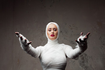 Beautiful young woman in bandages. Girl in a mummy costume, Pulling hand.