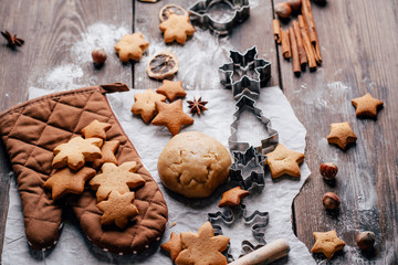 Freshly baked appetizing homemade gingerbread cookies, raw dough, baking utensils and food decorations. Christmas and New Year celebration traditions. Family home bakery, cooking festive sweets
