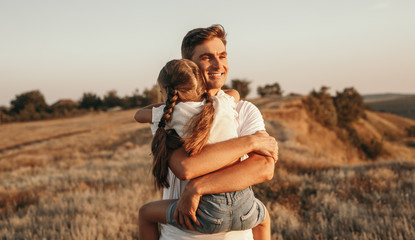 Happy father hugging daughter in field