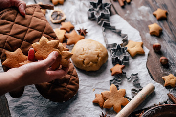 Freshly baked appetizing homemade gingerbread cookies, raw dough, baking utensils and food decorations. Christmas and New Year celebration traditions. Family home bakery, cooking festive sweets
