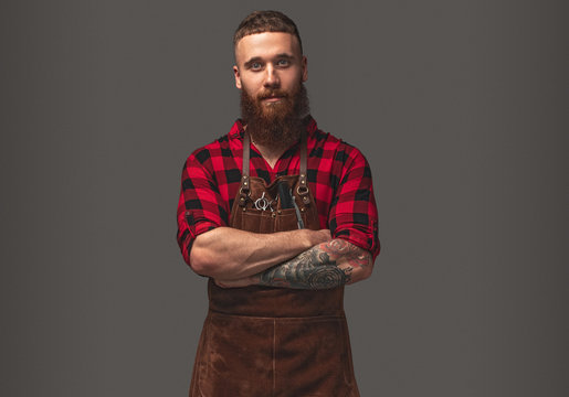 Confident stylish barber in bright checkered shirt with folded hand