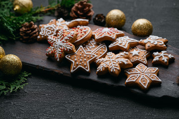 Christmas background with homemade gingerbread cookies, evergreen branches and decorations on black table. Festive food, New Year celebration traditions
