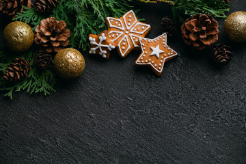 Christmas background with homemade gingerbread cookies, evergreen branches and decorations on black...