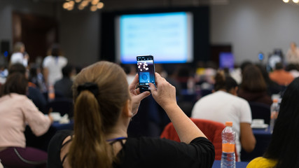 Girl taking a photo with a cell phone in a conference