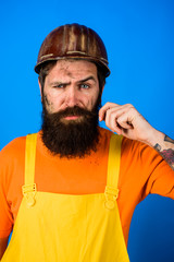 Bearded man in overalls and construction helmet. Mechanical worker. Industrial worker. Construction worker in hardhat. Business, building, industry, technology. Builder in hard hat. Man builder.