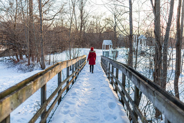 girl wearing red coat walking on the bridge over the river