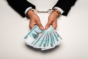 top view of businessman in handcuffs holding russian money on white
