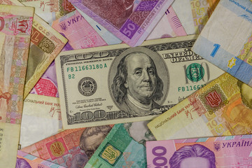 Fototapeta na wymiar One hundred dollar bill on a background of ukrainian hryvnia banknotes