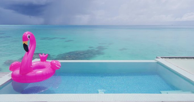 Funny vacation beach pool travel concept with inflatable pink flamingo float toy mattress in luxury swimming pool. Luxury lifestyle summer holidays travel background video.