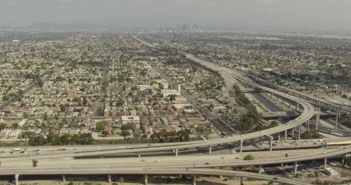 Aerial shot, day, side view of major la highway interchange and downtown at extreme distance, drone