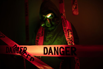 Portrait of a guy in a protective suit with green rubber gloves with a gas mask on his face and a...