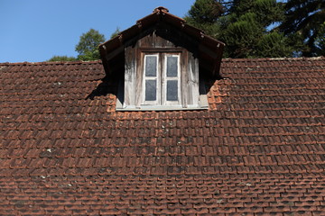 Rustic window in the roof of with red tiles of an old house