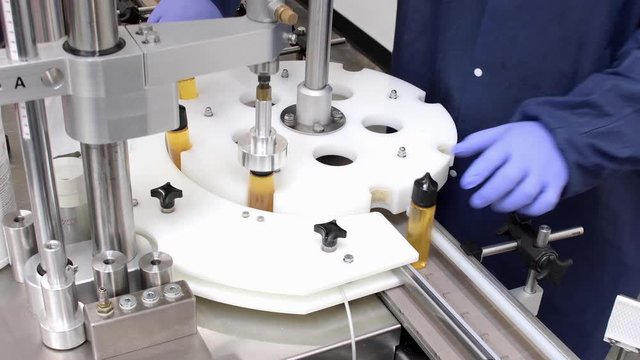worker on conveyer carousel filling bottles of e-liquid