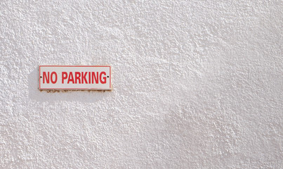 No parking sign with the white wall.
