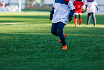 Boys in white and red sportswear plays  football on field, dribbles ball. Young soccer players with...