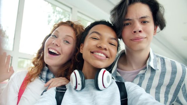Slow motion of funny teenagers multi-racial group taking selfie in school hall posing laughing having fun together. Modern lifestyle, people and photograph concept.
