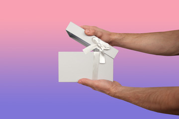man holding a gift in a light gray box with a satin ribbon and a bow, the concept of Valentine's Day, Christmas presents, mother's day, new year, close-up, copy space