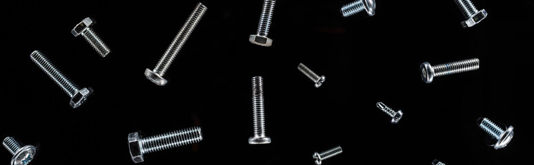 panoramic shot of scattered metal bolts pattern isolated on black