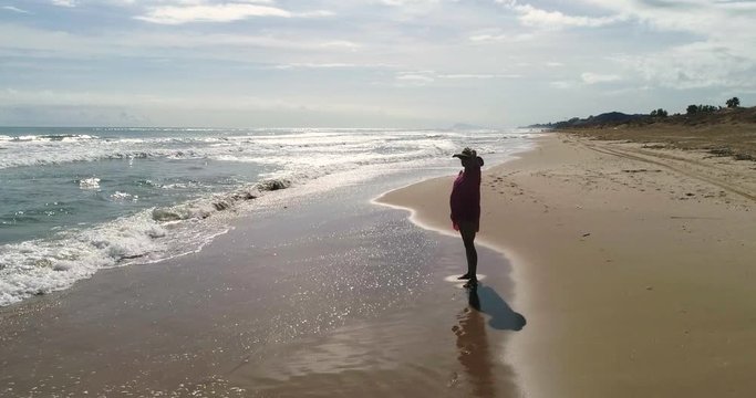 Mujer mirando al mar en playa paradis&iacute;aca y dron vuela alrededor
