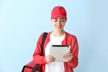 Female worker of food delivery service with tablet computer on color background