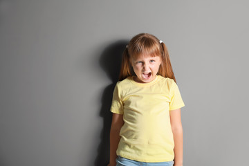 Portrait of angry little girl on grey background