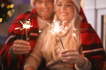 Happy mature couple with Christmas sparklers at home