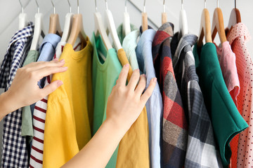 Woman choosing clothes hanging on rack