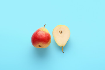 Whole and cut ripe pears on color background
