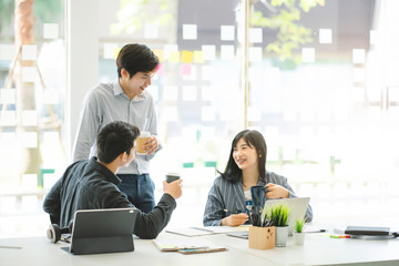 Business people talking during coffee break in modern office or coworking space. Young Asian business relaxing after working time.