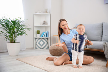 Mother teaching her little baby to walk at home