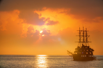 old pirate ship sailing at sea sunset