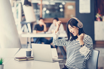 Fototapeta premium Cheerful young Asian girl celebrate after finish her work. Successful concept for small business start up, university education, new entrepreneur or freelancer.