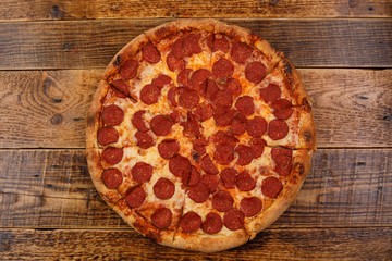 Traditional piperoni pizza on the wooden table. . The concept of delicious food.