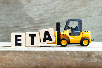Toy forklift hold letter block a to complete word ETA (abbreviation of estimated time of arrival) on wood background