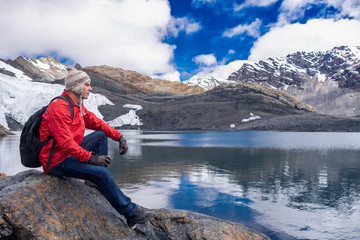 Hombre sentado junto a un lago en lo alto de los nevados