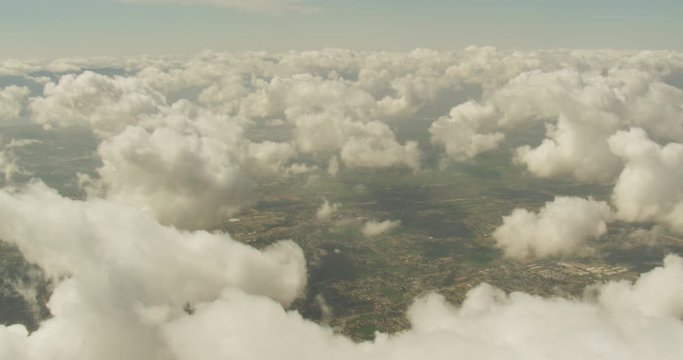 Aerial shot, day, examining town from above the cloudline, clouds surround the view, drone