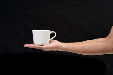 Man hand holding white coffee cup on black background