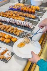 Woman selecting croissant at pastry counter at buffet party