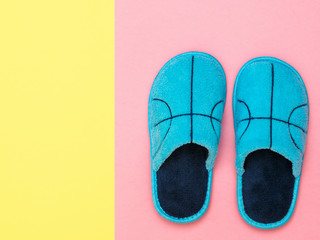 A pair of blue Slippers on a pink background next to a yellow background. The view from the top. Flat lay.
