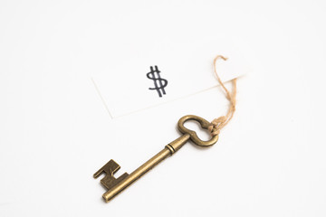 Old vintage brass key with dollar sign tag on white background