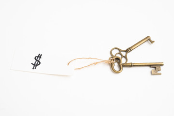 Old vintage brass key with dollar sign tag on white background