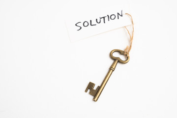 Old vintage brass key with solution word tag on white background