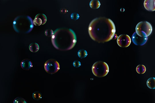 Rainbow soap bubbles colorful float on dark background