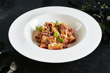 Exquisite Serving White Restaurant Plate of Homemade Rigatoni with Bolognese Sauce and Smoked Pork Belly