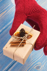 Hand of woman in gloves with gift for Christmas or other celebration