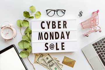 Creative promotion composition Cyber monday sale text on lightbox on white background, next grocery trolley, alarm clock, laptop, tablet. Banner for web design. Flat lay, top view, overhead, mockup
