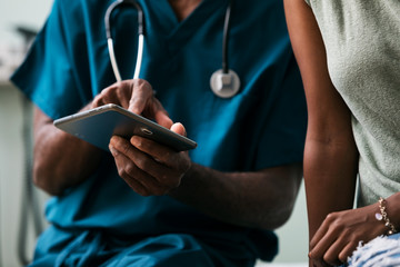 Exam: Doctor Shows Patient Information On Digital Tablet